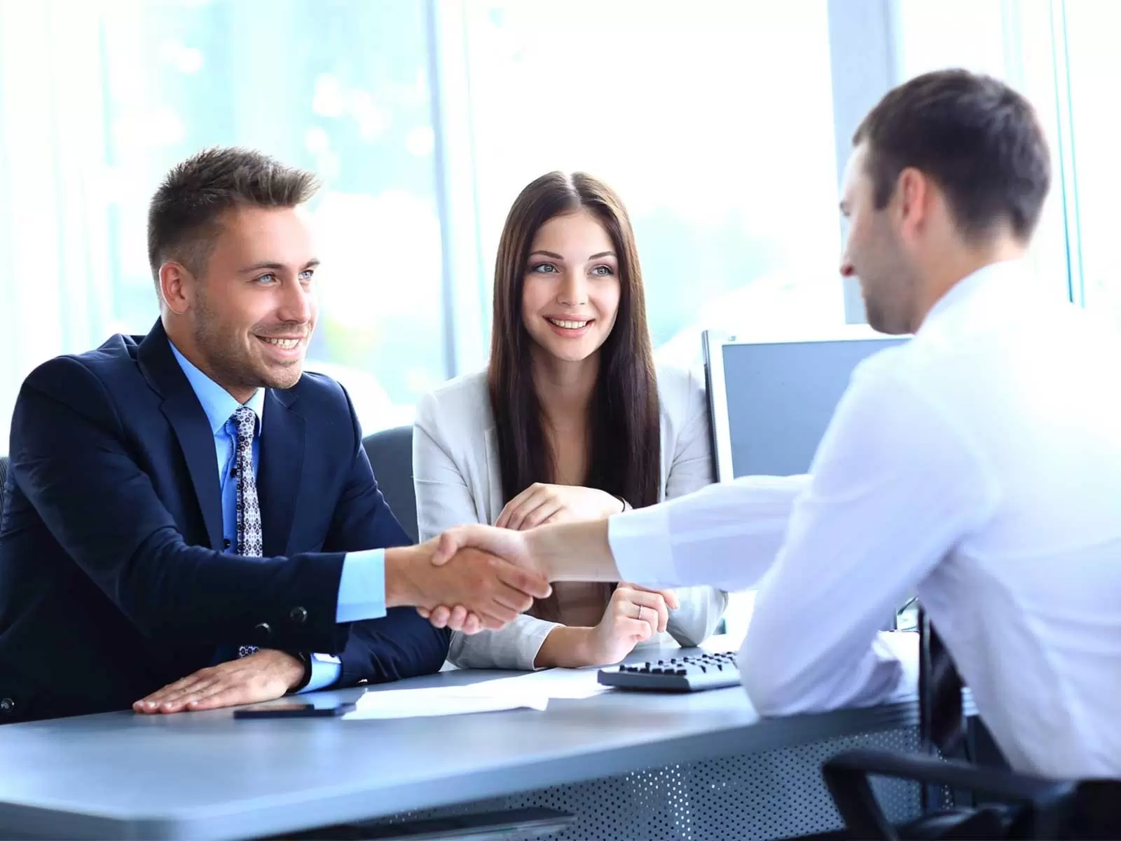 Pareja de hombre y mujer dandole la mano a otro hombre